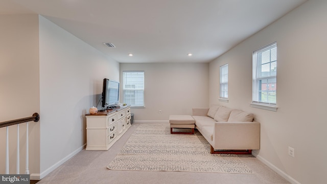 living room featuring light colored carpet, visible vents, plenty of natural light, and baseboards