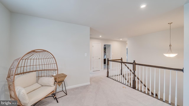 living area featuring recessed lighting, baseboards, light colored carpet, and an upstairs landing