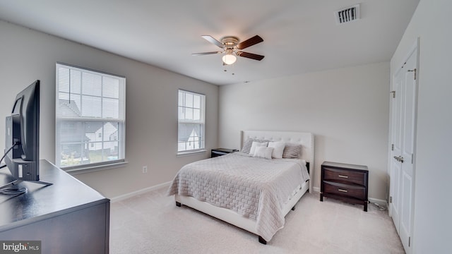 bedroom with light carpet, ceiling fan, visible vents, and baseboards