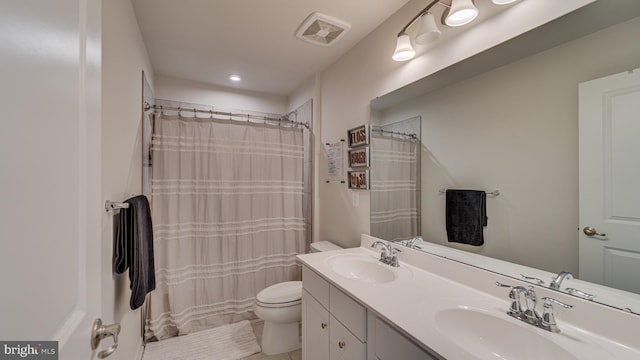 bathroom featuring toilet, double vanity, a sink, and visible vents