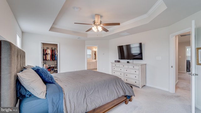 bedroom with light colored carpet, baseboards, a spacious closet, ornamental molding, and a tray ceiling