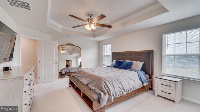 bedroom with ornamental molding, light colored carpet, a raised ceiling, and visible vents