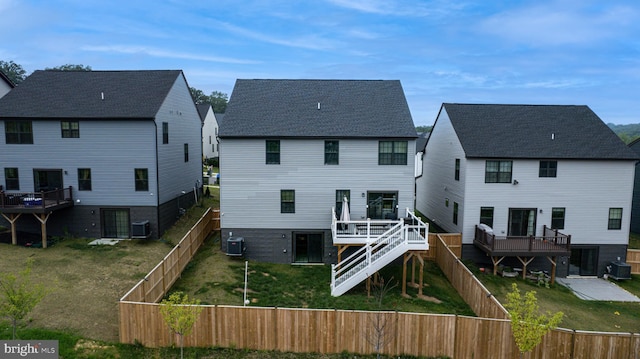 back of house with central AC unit, a lawn, a wooden deck, and a fenced backyard