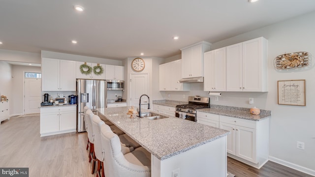 kitchen featuring appliances with stainless steel finishes, white cabinetry, a sink, and an island with sink