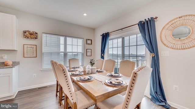 dining area with baseboards, visible vents, and wood finished floors