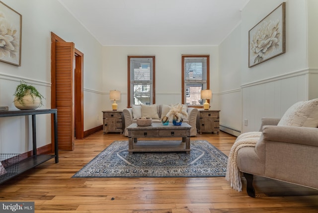 living room with wainscoting, baseboard heating, and wood finished floors