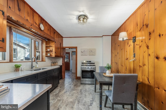 23 Swan St, Lambertville, NJ 08530 - kitchen featuring decorative backsplash, light countertops, wood walls, stainless steel range with gas cooktop, and a sink