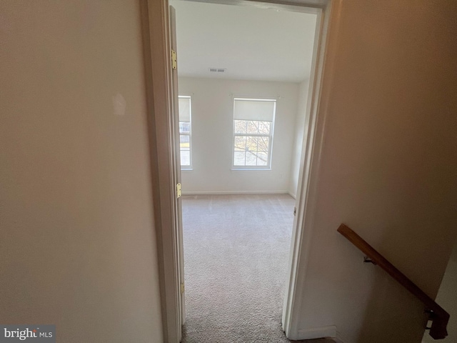 hallway with baseboards, carpet flooring, visible vents, and an upstairs landing