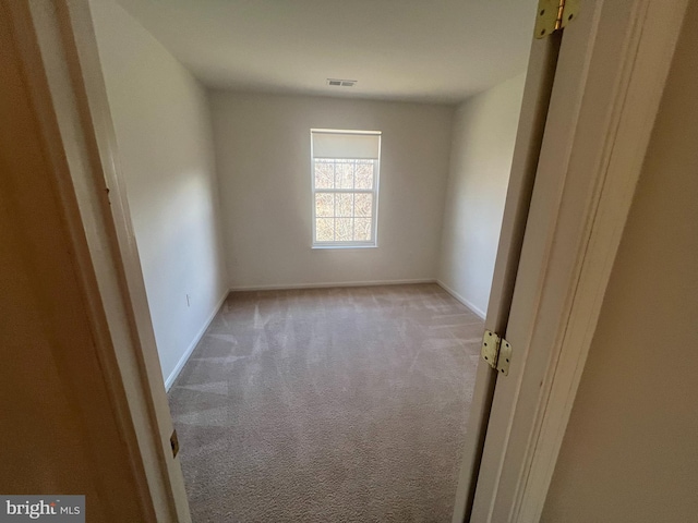 spare room featuring light carpet, visible vents, and baseboards