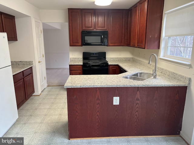 kitchen with reddish brown cabinets, light floors, a peninsula, black appliances, and a sink