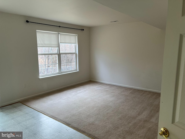 empty room with carpet floors, visible vents, baseboards, and tile patterned floors