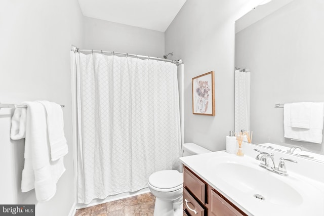 bathroom featuring toilet, stone finish flooring, and vanity