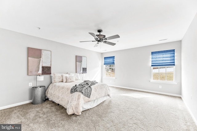 carpeted bedroom featuring a ceiling fan, visible vents, baseboards, and multiple windows