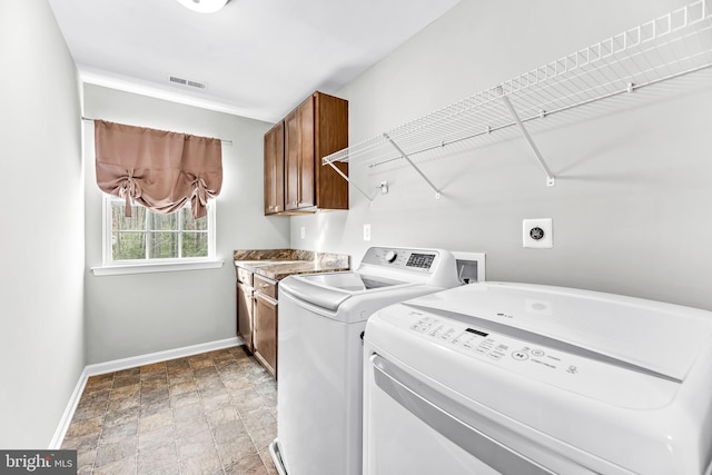 laundry room with cabinet space, visible vents, baseboards, stone finish flooring, and washing machine and dryer