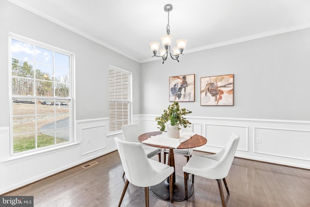 dining space featuring a notable chandelier, visible vents, ornamental molding, wainscoting, and hardwood / wood-style floors