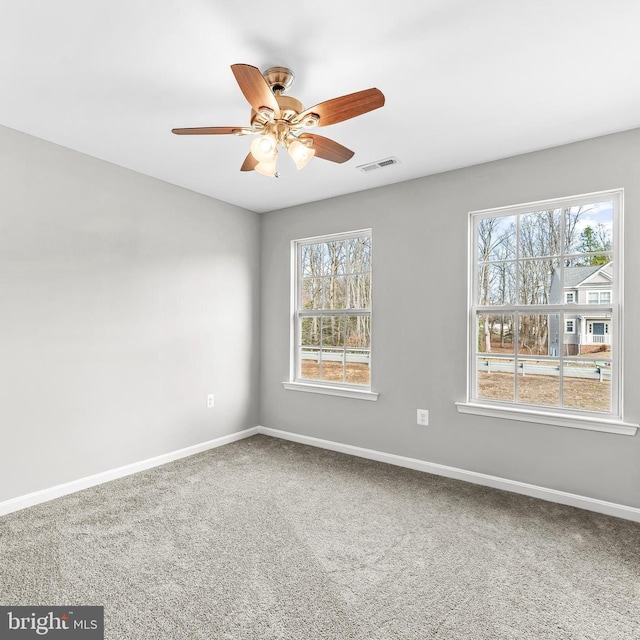 carpeted spare room with a ceiling fan, visible vents, and baseboards