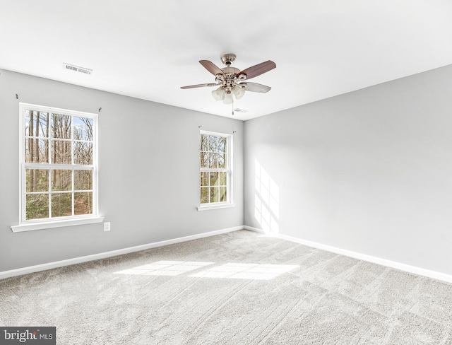 empty room with baseboards, plenty of natural light, visible vents, and carpet flooring