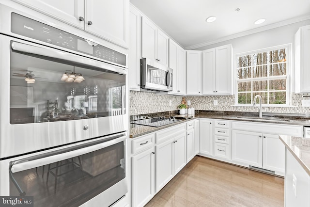 kitchen with white cabinets, appliances with stainless steel finishes, backsplash, and a sink