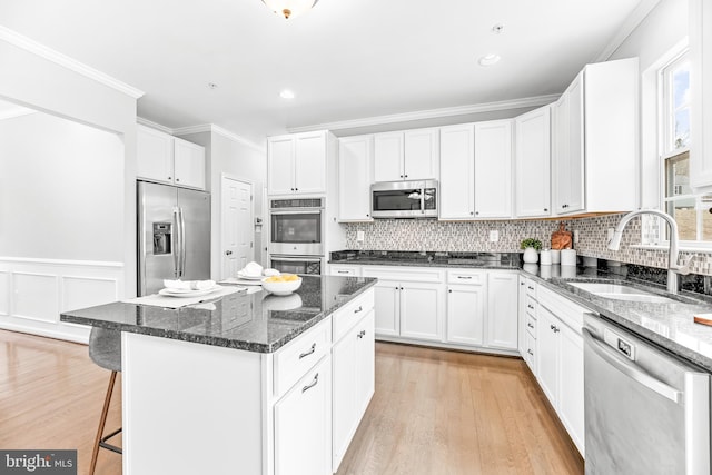 kitchen with a kitchen island, a breakfast bar area, stainless steel appliances, crown molding, and a sink