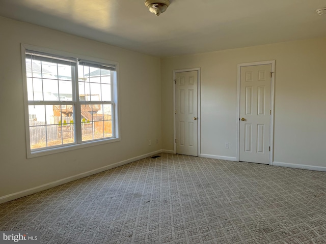 carpeted spare room featuring visible vents and baseboards