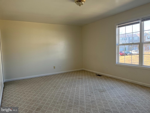 unfurnished room featuring carpet floors, plenty of natural light, visible vents, and baseboards