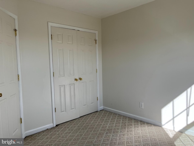 unfurnished bedroom featuring a closet, carpet flooring, and baseboards