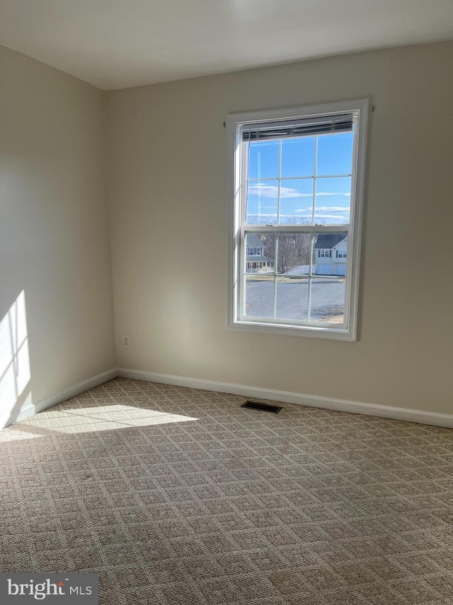 carpeted empty room featuring visible vents and baseboards