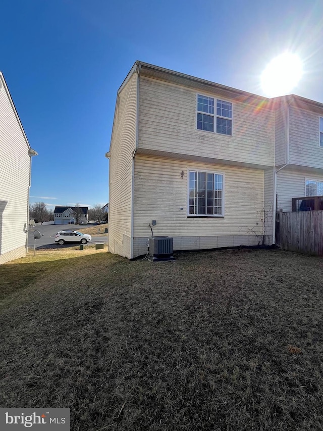 back of property with a yard, fence, and central air condition unit