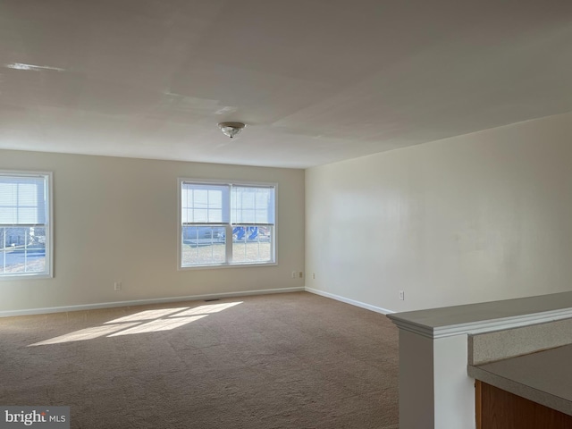 carpeted spare room featuring baseboards