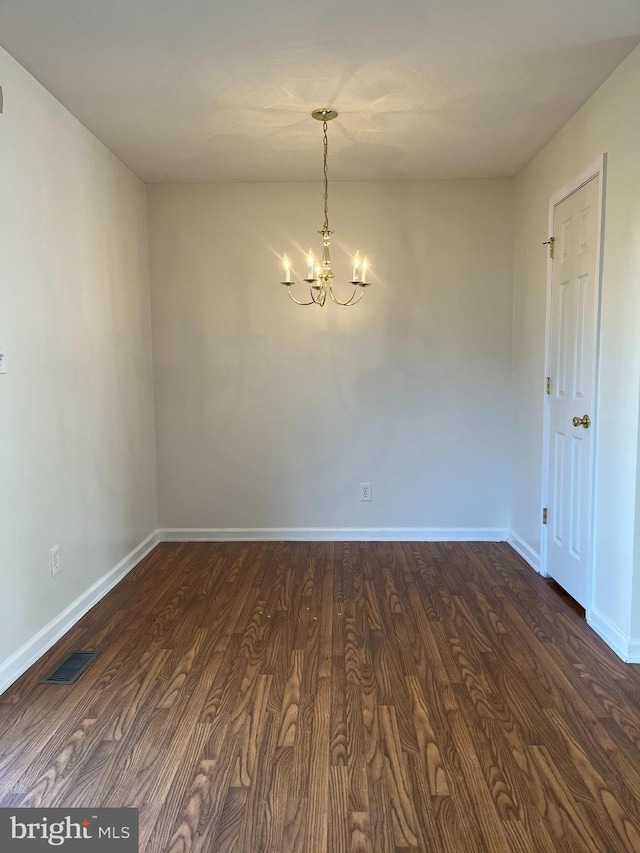 unfurnished room with dark wood-style floors, baseboards, visible vents, and a notable chandelier