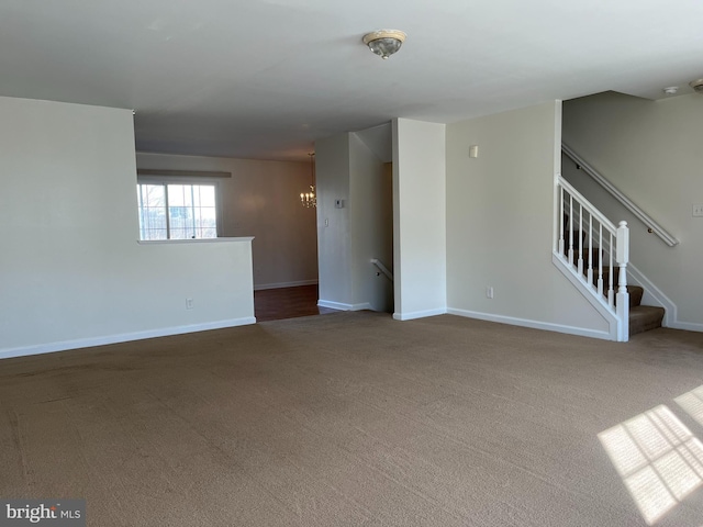 carpeted empty room featuring stairs and baseboards