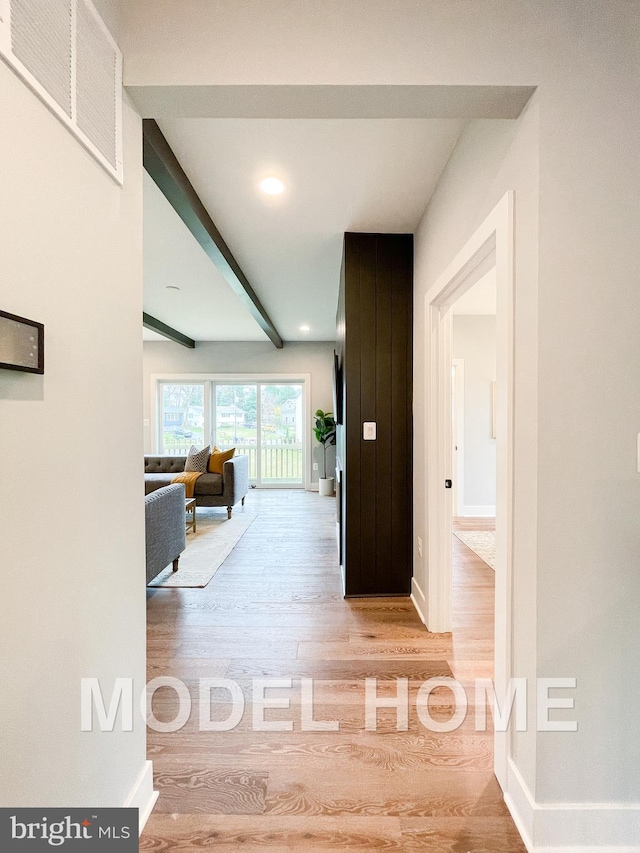 corridor featuring beam ceiling, wood finished floors, visible vents, and baseboards