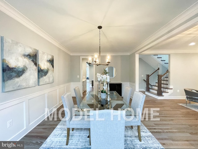 dining area featuring stairs, crown molding, wood finished floors, and a chandelier