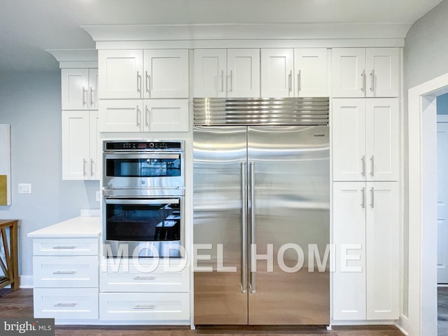 kitchen with light countertops, appliances with stainless steel finishes, dark wood-type flooring, and white cabinets