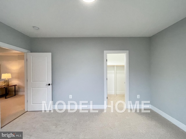 unfurnished bedroom featuring carpet floors, a walk in closet, and baseboards