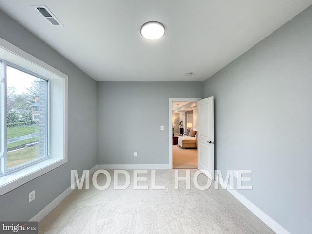 carpeted spare room featuring baseboards and visible vents