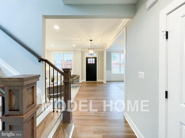 entryway with stairs, ornamental molding, light wood-style flooring, and baseboards