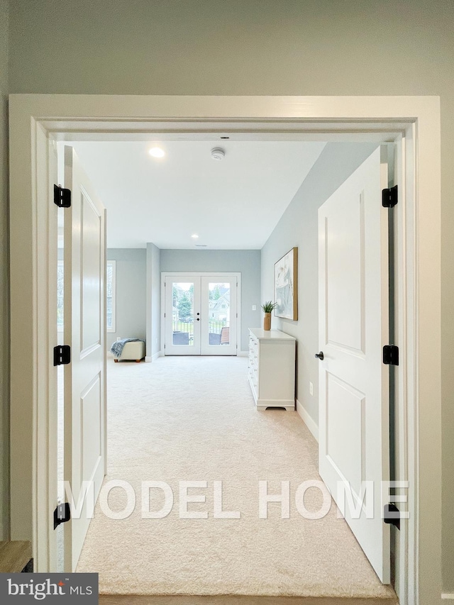 hall featuring carpet, baseboards, and french doors