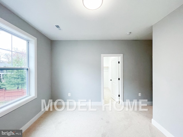 carpeted spare room with visible vents and baseboards