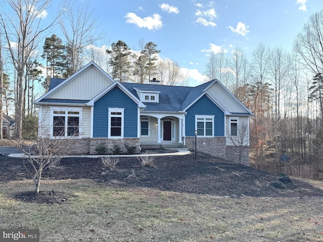 view of front of house with stone siding, a chimney, and a shingled roof