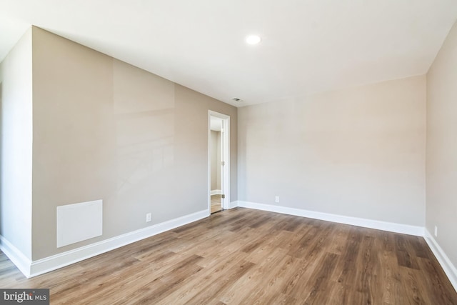 unfurnished room with wood finished floors, visible vents, and baseboards