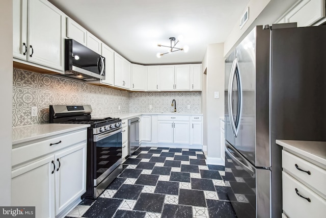 kitchen with appliances with stainless steel finishes, light countertops, a sink, and white cabinetry