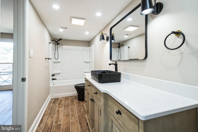 full bathroom with toilet, wood finish floors, vanity, baseboards, and washtub / shower combination