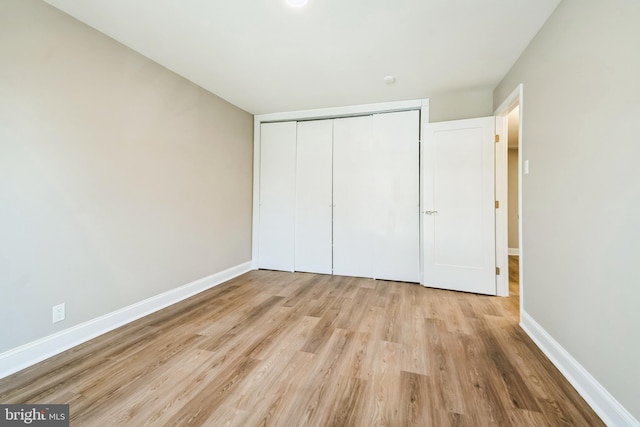 unfurnished bedroom with a closet, wood finished floors, and baseboards