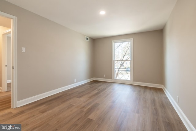 unfurnished room featuring visible vents, baseboards, and wood finished floors