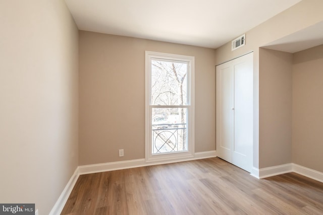 unfurnished bedroom with light wood-type flooring, a closet, visible vents, and baseboards