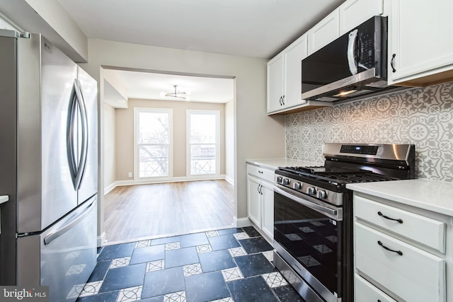 kitchen featuring white cabinets, stainless steel appliances, decorative backsplash, and light countertops