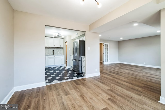 empty room featuring a sink, recessed lighting, wood finished floors, and baseboards