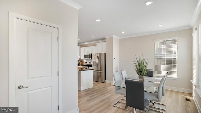 dining area with light wood finished floors, visible vents, and crown molding