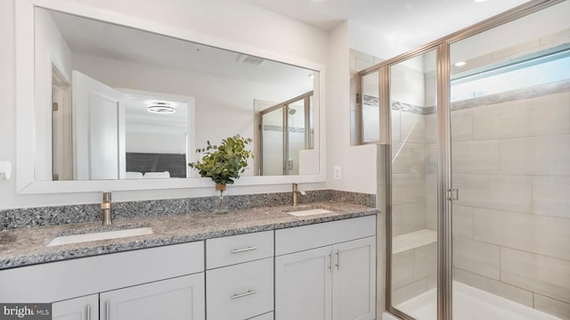 bathroom featuring double vanity, a stall shower, and a sink